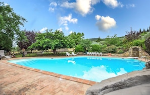 A swimming pool with a brick deck, surrounded by trees and a stone wall. - Stunning home in Magione (Magione)