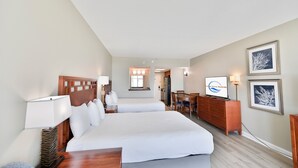 Ein Hotelzimmer mit zwei Betten, einem Schreibtisch, einem Stuhl, einem Schminktisch und einem Fernseher.