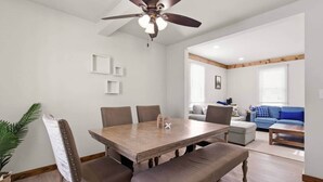 A dining area with a wooden table and chairs, a ceiling fan, and a view into a living room with a sofa and a window. - Farmhouse less than a mile from beaches (Millcreek Township)