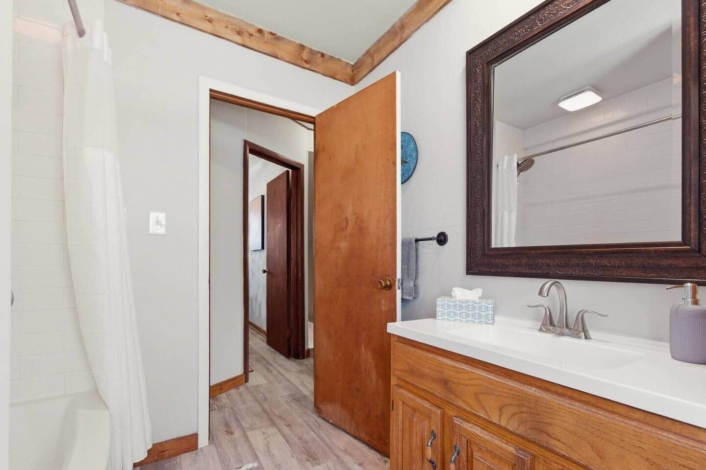 Un baño con tocador de madera, un espejo grande y un perchero para toallas.