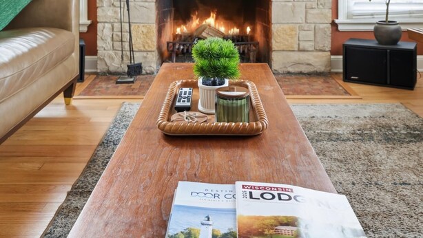 Un salon chaleureux avec une cheminée, une table basse en bois, une plante en pot et un magazine posé sur la table.