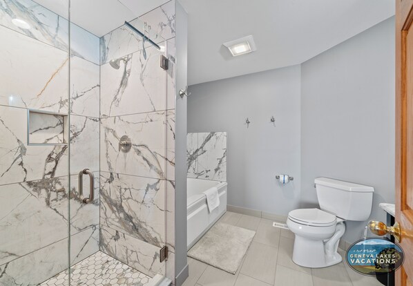 A bathroom with a glass-enclosed shower, a white toilet, and a bathtub. - Pickleball Court | Lake Views | Pool Table | Sleeps 10 (Twin Lakes)