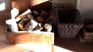 Una pared de piedra rústica, una puerta de madera, una cesta de leña y una cesta de mimbre.
