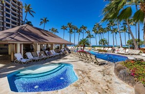 A hotel pool area with lounge chairs, a small pool, and palm trees. - Maui Resort Rentals: Kaanapali Alii 352/3 - 5th-Floor 4BR Retreat with Ocean and Mountain Views! (Lahaina)