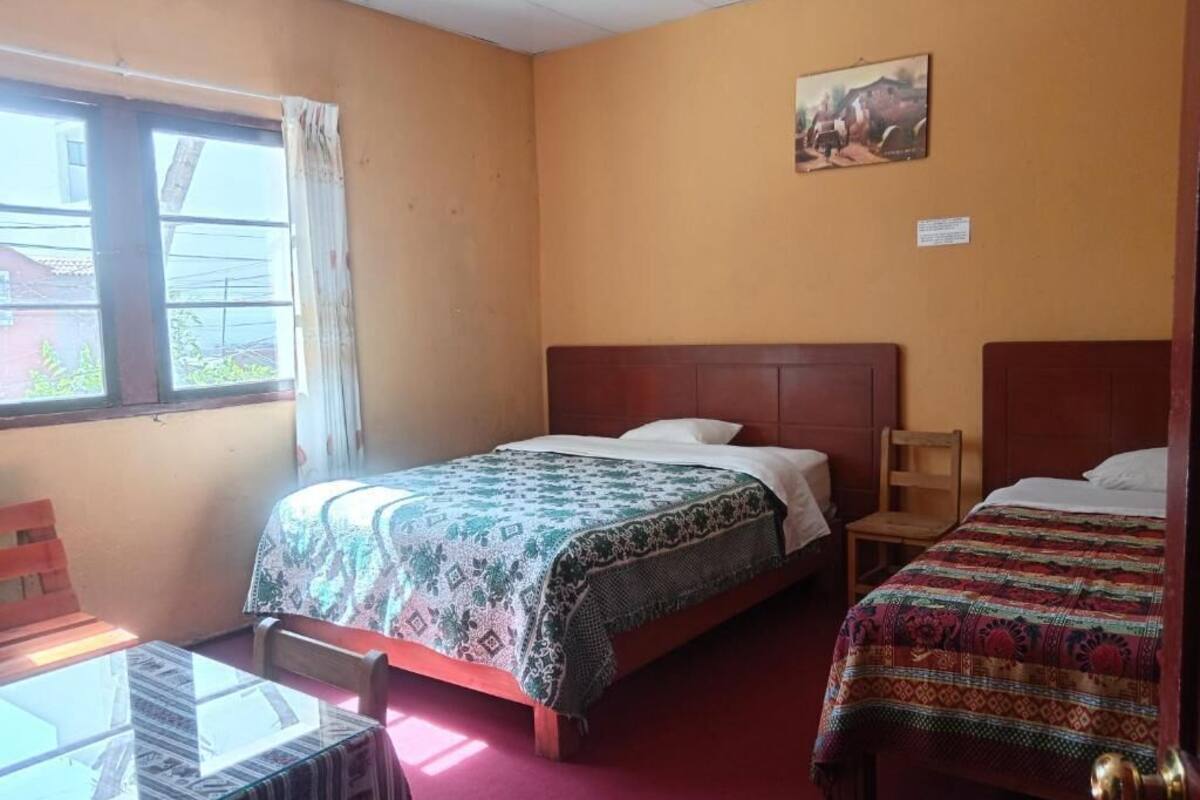 A room with two beds, a table, and a window.