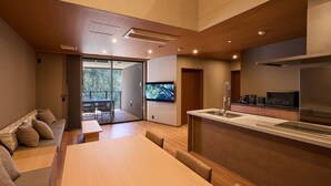 Una cucina moderna con piano cottura integrato, una zona pranzo con tavolo e sedie in legno, e una porta scorrevole in vetro che dà su un patio esterno.