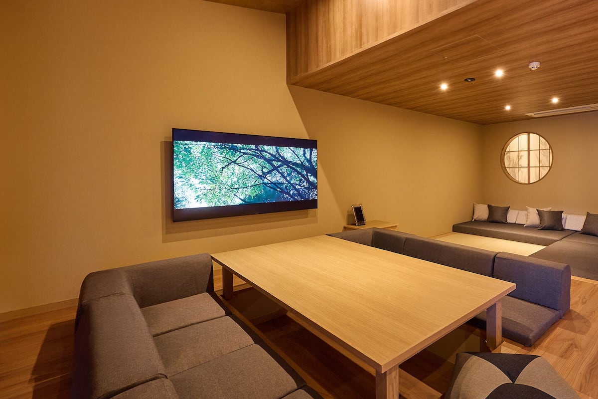 A modern interior with a wooden ceiling, a large flat-screen TV, a sofa, a table, and a circular window.