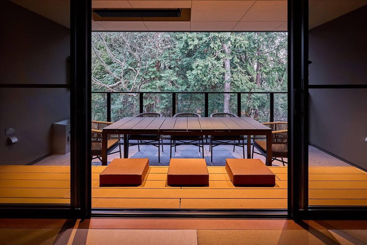 An interior view of a room with a wooden floor, a table with chairs, and a bench.