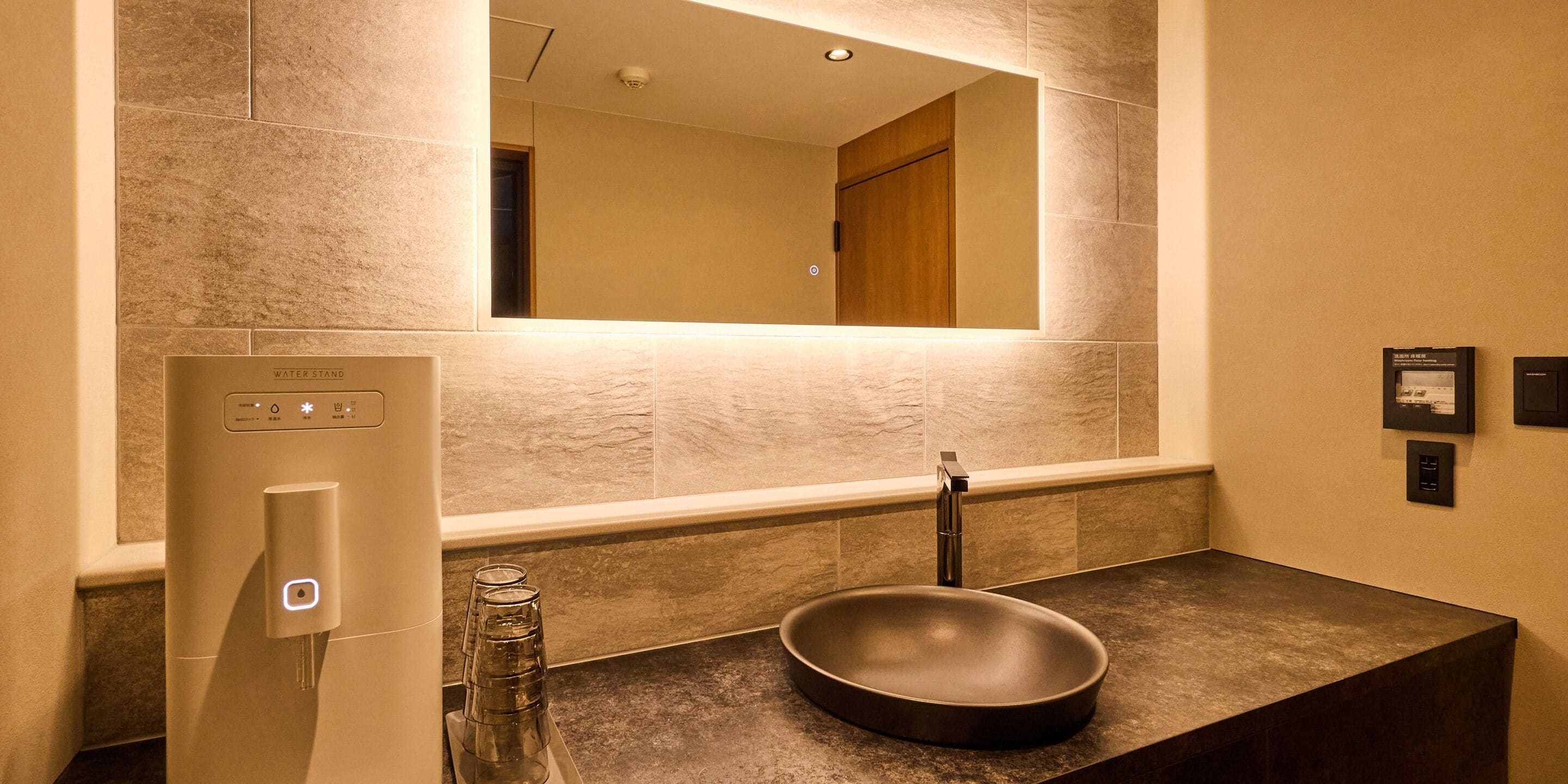 A bathroom with a modern sink, a water stand, and a mirror.