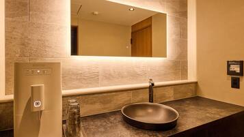 A bathroom with a modern sink, a water stand, and a mirror.