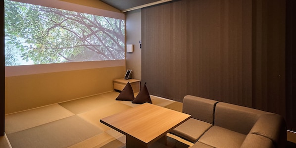 A room with tatami flooring, a wooden table, a sofa, and a projection screen displaying a tree. - Rakuten STAY VILLA Hakone Gora (Hakone)