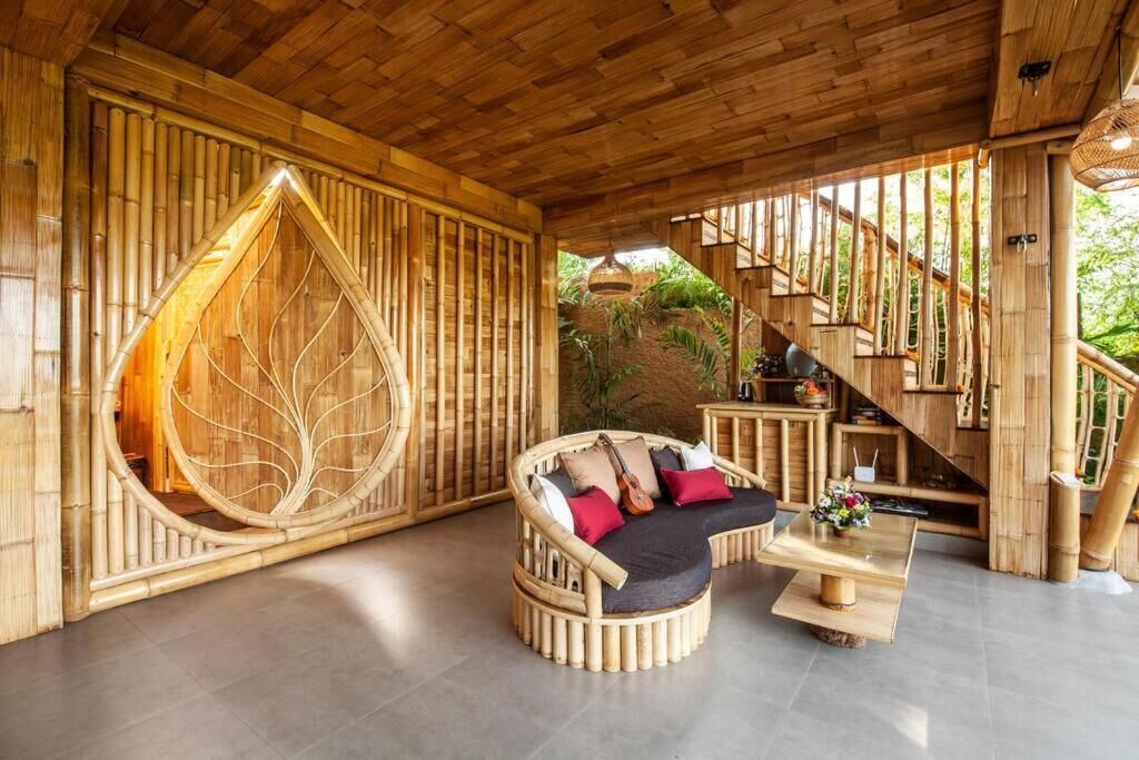 Een interieur met bamboe details, een gebogen bank, een hangstoel en een trap.