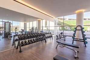 A modern gym with various weightlifting equipment, large windows, and a view of the outdoors. - New Luxury Oceanview Golf Resort, Pool and Hot-tub (San José del Cabo)