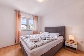A bedroom with a bed, a nightstand, a lamp, and a window with curtains. - Pool Apt 1 - Novi Vinodolski (Sea View), Novi Vinodolski, Croatia (Novi Vinodolski)