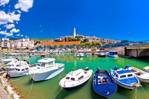 Un port amb vaixells amarrats, un pont i edificis al fons.