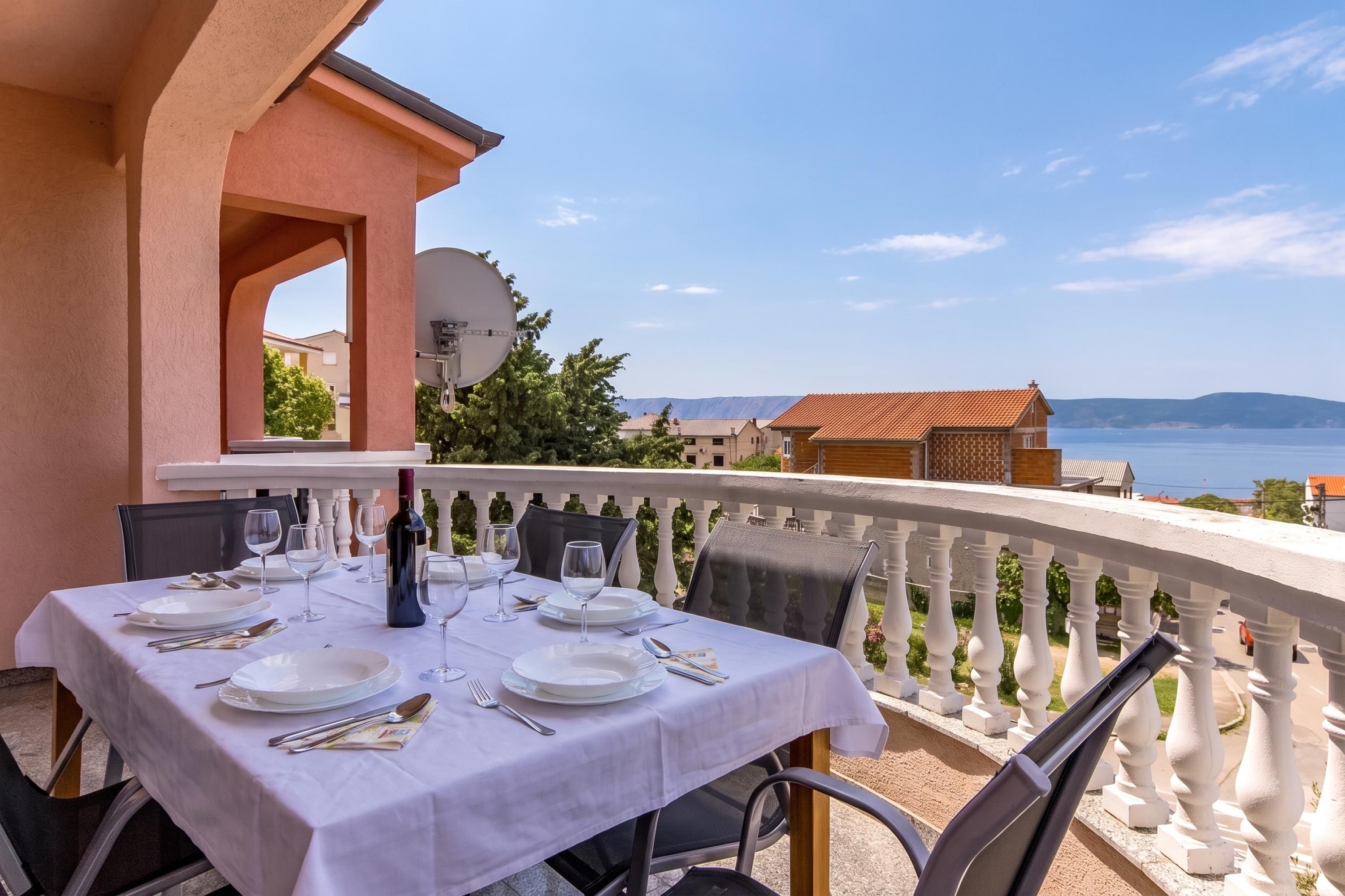 A table set for dining with a view of the sea and mountains.