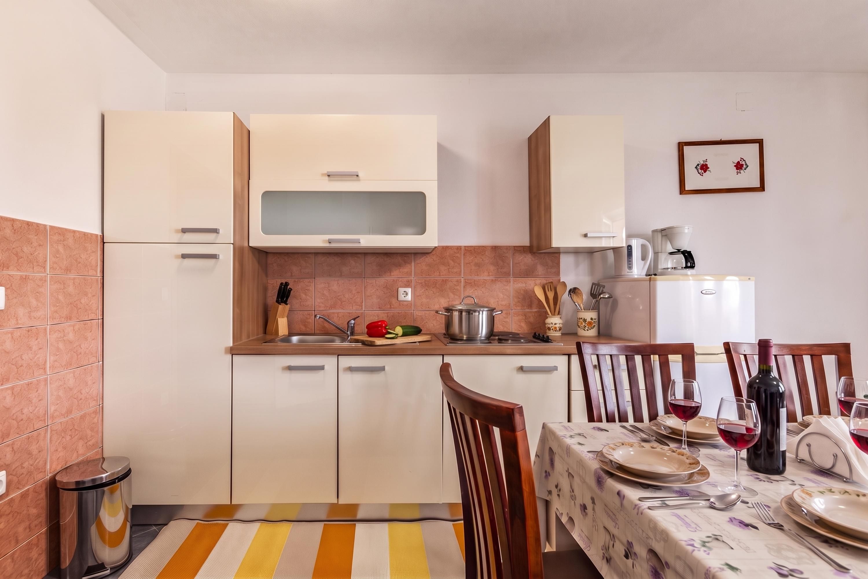 A compact kitchen with a dining area, equipped with basic appliances and a dining table set for two.