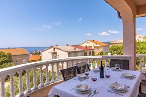 A balcony with a table set for dining, overlooking a coastal view with buildings and the sea. - Pool Apt 1 - Novi Vinodolski (Sea View), Novi Vinodolski, Croatia (Novi Vinodolski)