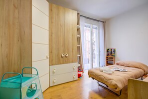 Ein Schlafzimmer mit einem Bett, einem Kleiderschrank, einem Fenster und einem Regal mit Büchern.