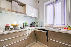 Eine moderne Küche mit Gasherd, Edelstahlgeräten und einem Fenster mit violetten Vorhängen.