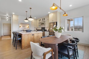 A modern kitchen with wooden cabinets, a central island, and pendant lighting. - Canyon Trail Luxury Stay (Twin Falls)