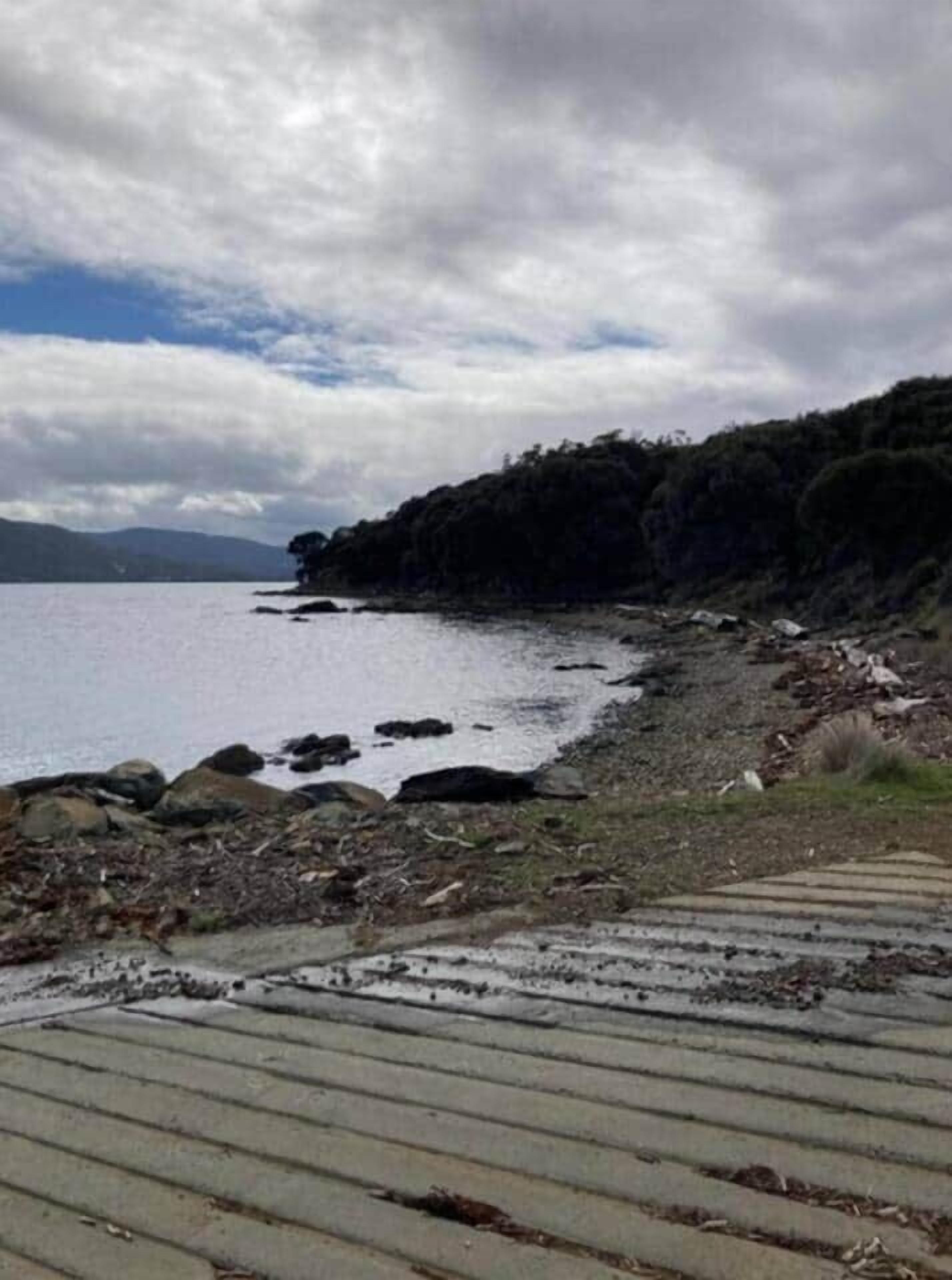 Una passeggiata costiera che conduce a una scogliera rocciosa, con vista sul mare e su montagne lontane.
