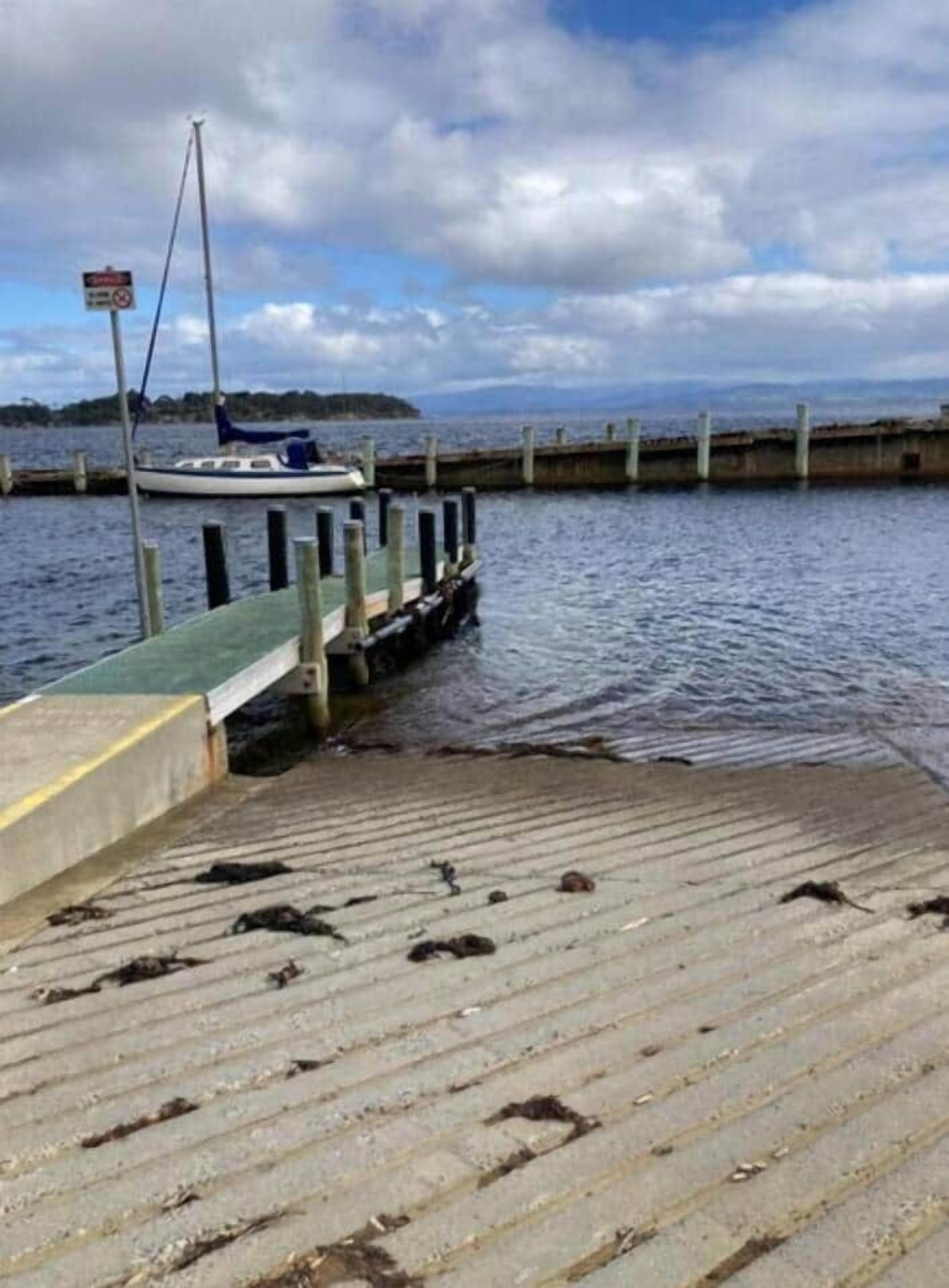 A wooden pier extending into calm water with a boat docked at the end.