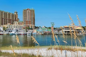 A marina with boats, a tall hotel, and a small tower structure. - ✨Walk 2 Beach~ Jetty Retreat✨ (Destin)