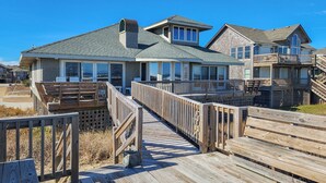 A beachfront property with a wooden boardwalk leading to a house with large windows and a covered deck. - AMES - 4 BR Oceanfront home w/Ocean Views & Elevator (Southern Shores)