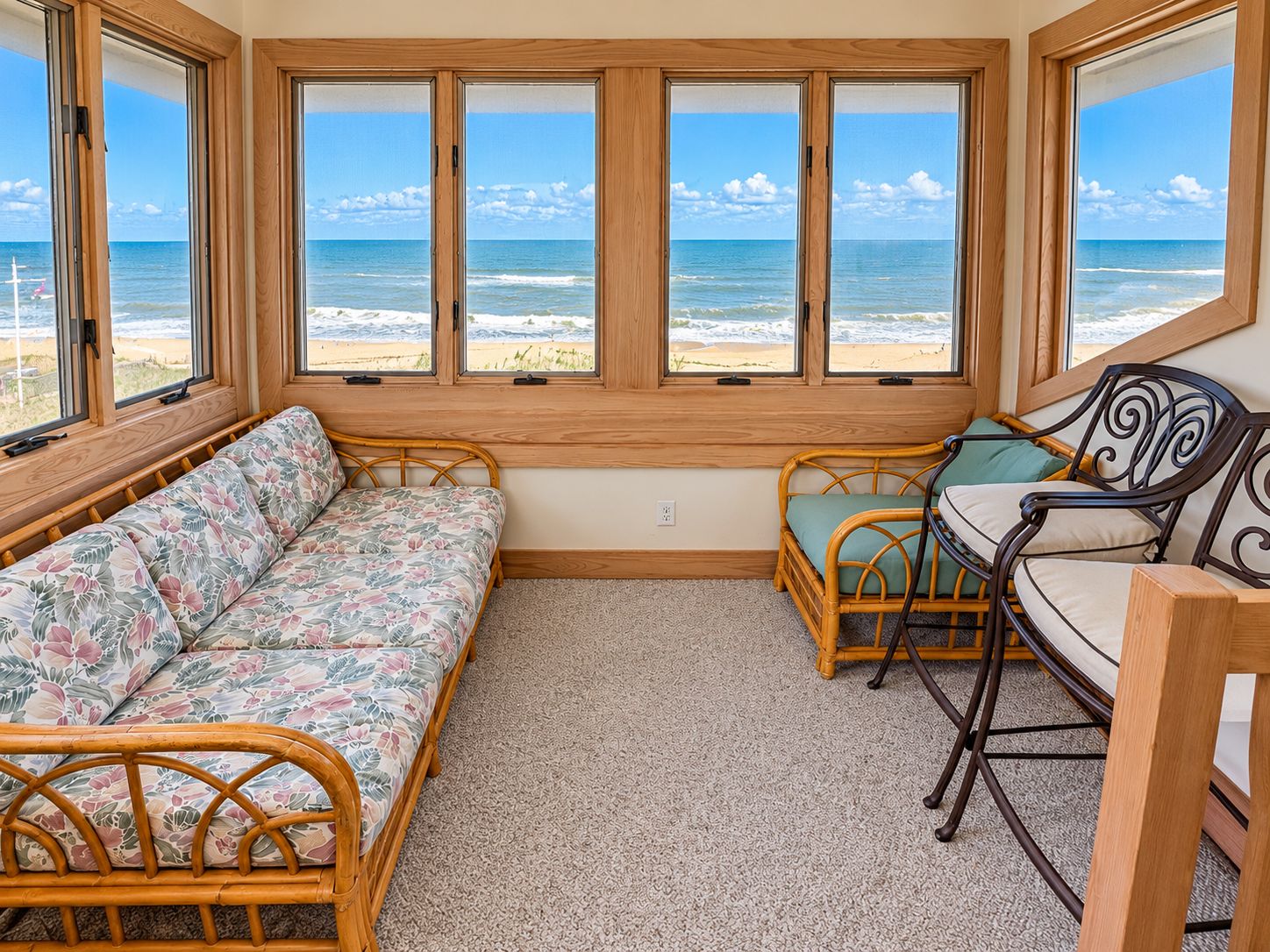 A room with a view of the beach, a sofa, a chair, and a small table.