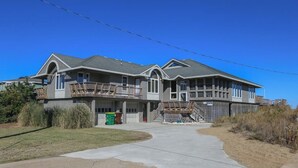 A two-story house with a balcony, a garage, and a driveway. - AMES - 4 BR Oceanfront home w/Ocean Views & Elevator (Southern Shores)