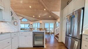 Una cocina moderna con armarios blancos, un refrigerador de acero inoxidable y un horno empotrado.