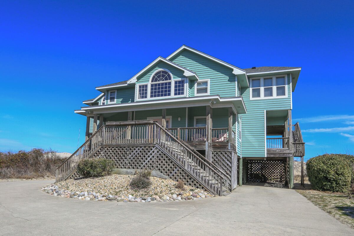 A two-story house with a front porch, a staircase, and a small deck.