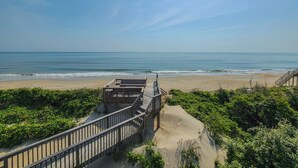 Una pasarela de madera que conduce a una playa con vista despejada al océano.