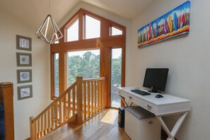 A spacious room with a wooden staircase, a desk with a computer, and a large window offering a view of trees. - GONE COASTAL - 5 BR Hone in Southern Shores w/Private Pool & Hot Tub (Southern Shores)