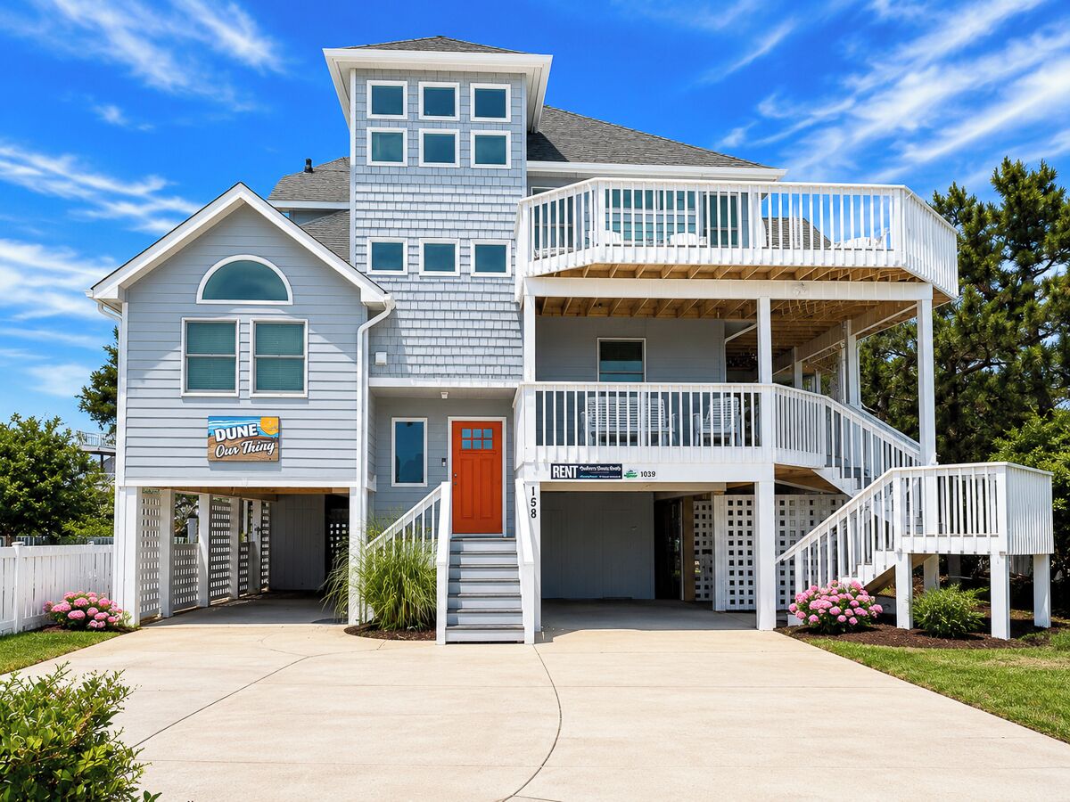 A two-story house with a front porch, a garage, and a sign indicating it is for rent.