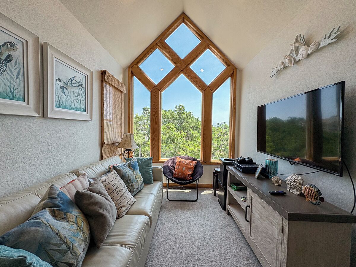 A living room with a large window, a sofa, a chair, a TV, and a cabinet.