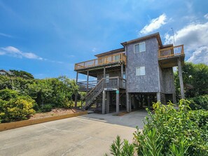 A two-story building with a wooden deck and a staircase leading to the upper level. - SNOW GOOSE - 4 BR Semi-Oceanfront Home, Just 1 Lot From The Ocean (Duck)