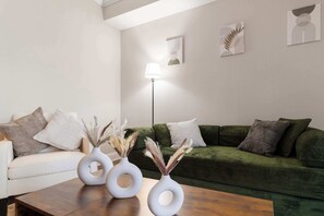 A living room with a white sofa, green sofa, and a wooden coffee table with three white vases. - FIFA 26 Modern 1BR Midtown • Pool • Gym • Parking (Atlanta)