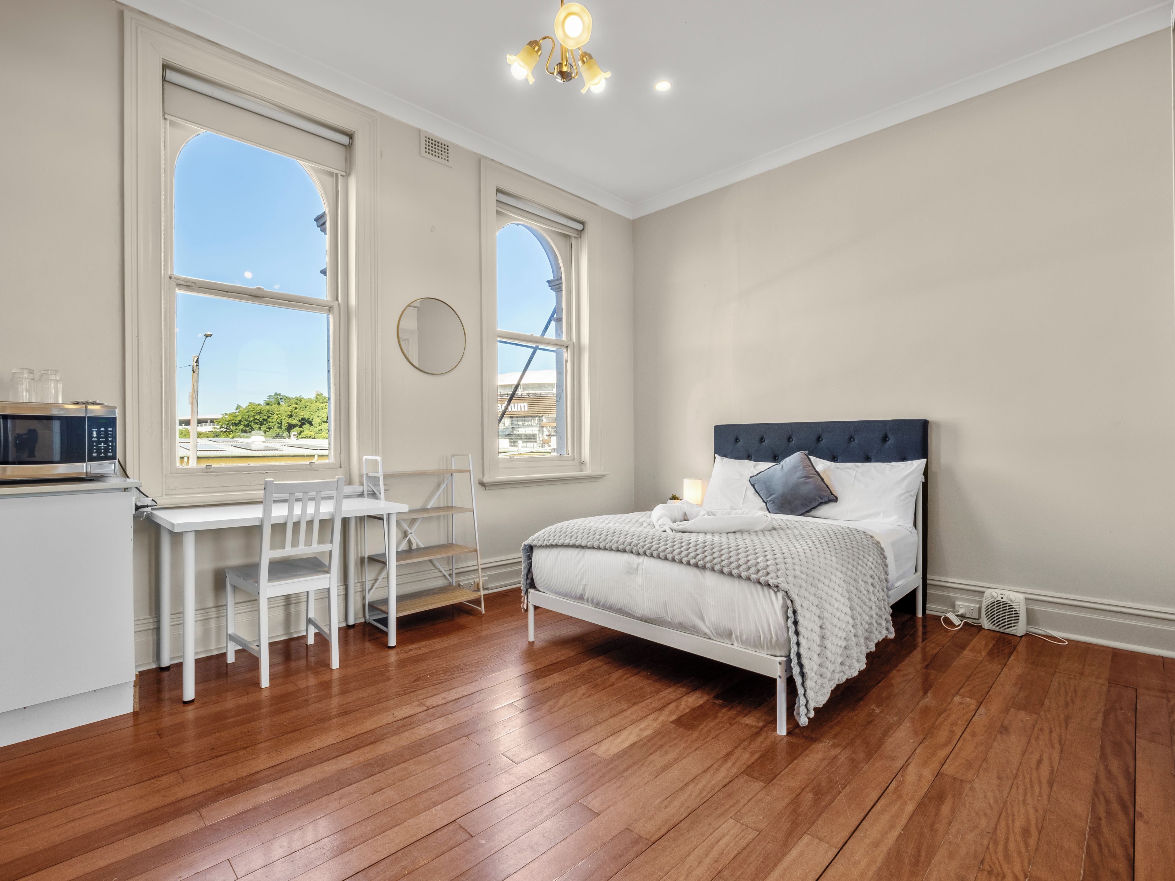 A bedroom with a bed, a desk, and a chair.