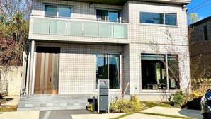 A modern two-story house with a tiled facade, large windows, and a visible garage door.