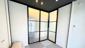 A room with a sliding glass door, a bed with a beige blanket, and a white tiled floor.