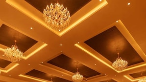 A spacious room with a patterned carpet, multiple chandeliers, and recessed lighting. - Aureva Raj Bagh Retreat (Jaipur)