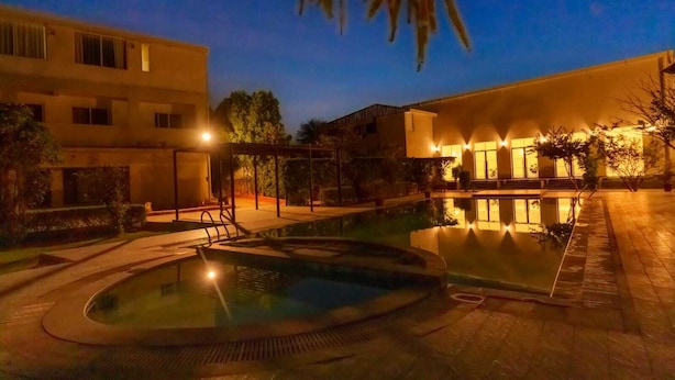 A swimming pool area with a hot tub, surrounded by buildings with warm lighting. - Aureva Raj Bagh Retreat (Jaipur)