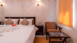 A hotel room with a bed, a chair, a small table, and a wall-mounted projector. - Aureva Raj Bagh Retreat (Jaipur)