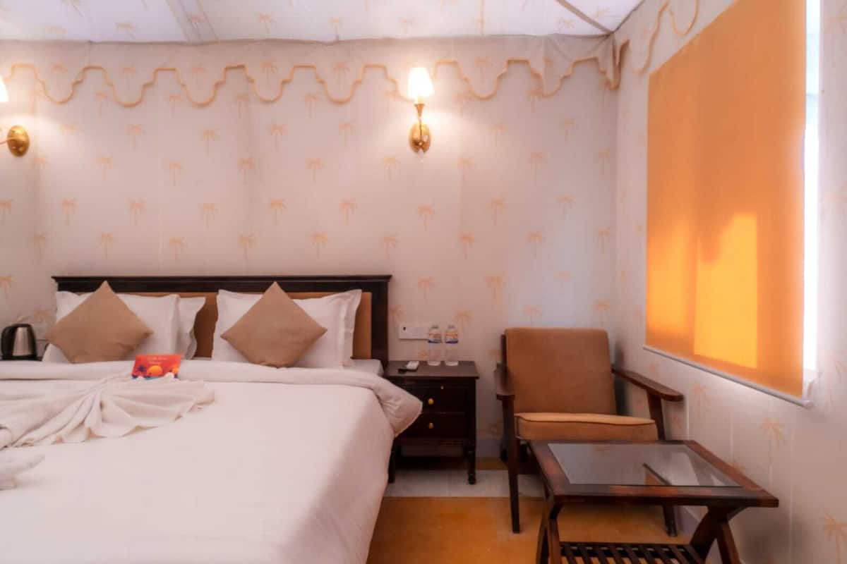 Une chambre d’hôtel équipée d’un lit, d’une chaise, d’une petite table et d’un projecteur fixé au mur.