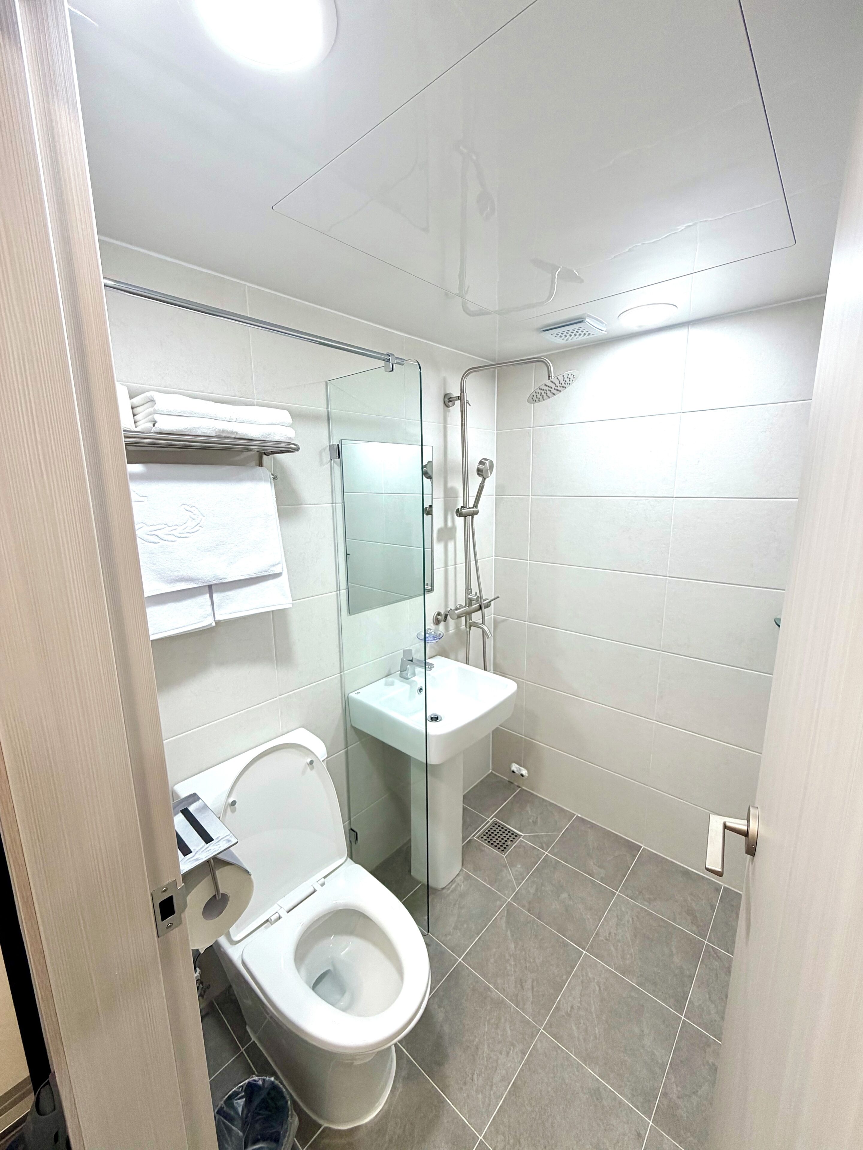 A bathroom with a toilet, a glass-enclosed shower, and a sink.