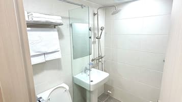 A bathroom with a toilet, a glass-enclosed shower, and a sink.