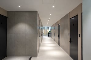 A modern hallway with a long corridor, doors, and recessed lighting.