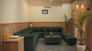 Un salon moderne avec un canapé d’angle vert, une table basse en bois et une plante en pot.